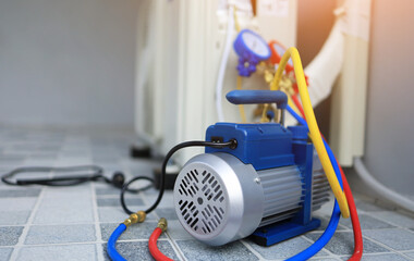 The back vacuum unit is placed beside the outdoor air conditioner unit and manifold gauge to use in...