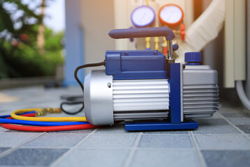 The vacuum unit is placed beside the outdoor air conditioner unit and manifold gauge for use in...