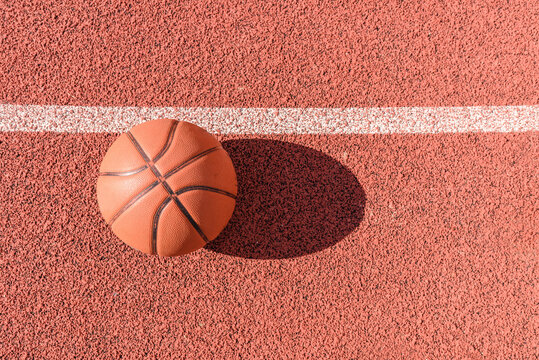 Old orange ball for basketball lying on the rubber sport court.Sport red ground outdoor in the yard.Top view,Copy space.