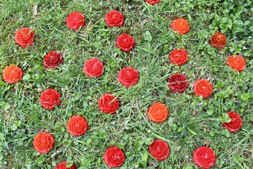 Red flowers on concrete floor. Red beeswax hand-poured candles placed on old vintage concrete steps with dried leaves and moss