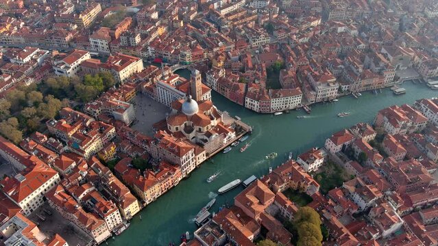 Beautiful aerial view of San Geremia Church and Grand Canal located in the sestiere of Cannaregio district in Venice, Italy. Flying over of medieval romantic city looking down to boats at sunset in 4K