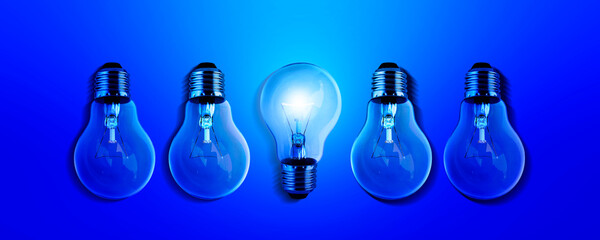 Light bulbs illuminate a row of dim lighting ideas for creativity, innovation and solutions