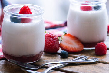 Two strawberry yogurt milk shakes with fresh strawberries on a table next to ingredients