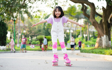 Fototapeta premium Asian little girl practicing roller skating in the park