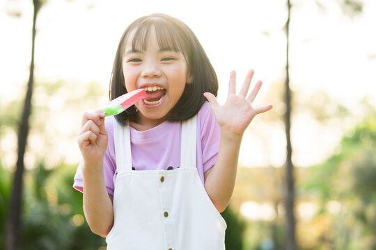 Image of Asian little girl eating ice cream at park