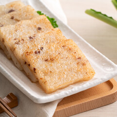 Delicious Chinese radish cake in a plate on wooden table background.