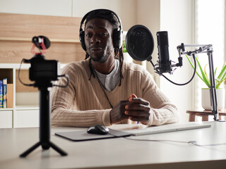 afroamerican  happy young male recording audio blog in headphones microphone broadcasting at home ...