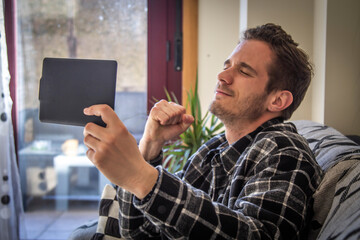 man at home with  tablet and expression of success