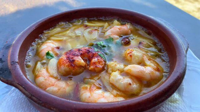 Traditional sizzling Spanish Gambas pil pil in a restaurant in Marbella Spain, delicious spicy shrimp dish with garlic, 4K static shot
