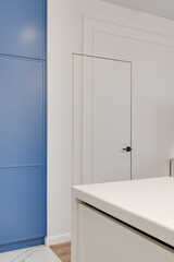 Close-up of an interior design element with white wall and door and blue cabinet