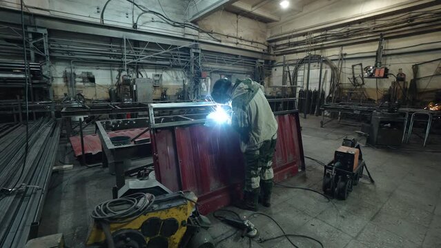 A worker cooks metal on a welding machine in production. a worker with a welding machine to cook parts