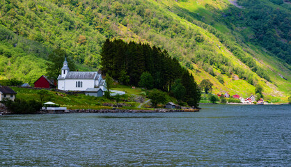 Traditional white Christian church in amazing Aurlandsfjord with small wooden houses