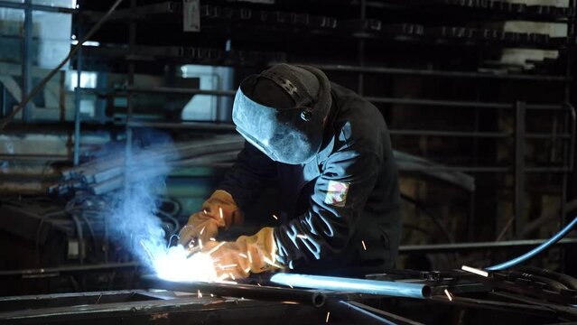 A worker cooks metal on a welding machine in production. a worker with a welding machine to cook parts