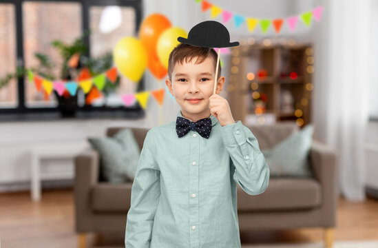 birthday party, childhood and people concept - portrait of little boy with bowler hat over decorated home room background