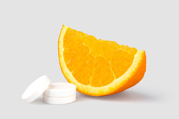 Vitamin C effervescent tablet with slice of fresh orange next to it. 