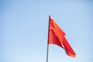 Red flag against the sky. Red matter on a stick.