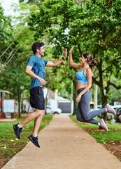 That workout was so worth it. Shot of a sporty young couple high fiving in mid-air while exercising outdoors.