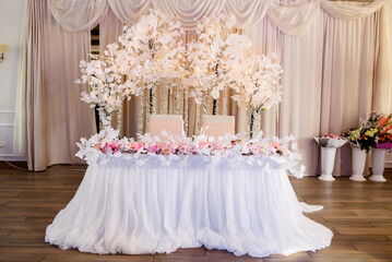 Stylish table setting with dried flowers. Plate with vintage golden fork and knife, candles, dusty blue napkins on wooden table. Winter wedding decoration.