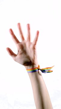 Raised arm wearing a bracelet with the colors of the LGBT flag. LGBT symbol. Vertical video.