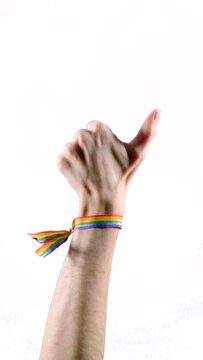 Hand wearing a bracelet with the colors of the LGBT flag raising thumb. LGBT symbol. Vertical video.