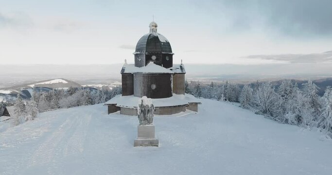approach to the frozen Radhost chappel with pan up during a morning golden hour in winter, Beskydy 4k