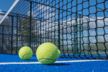 selective focus, paddle tennis balls on a blue paddle tennis court close to the net, racket sports concept