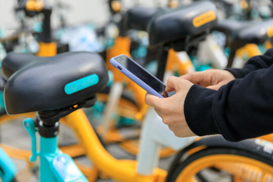 Hands using smartphone scanning the QR code of shared bike in city