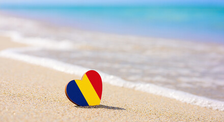 Flag of Romania in the shape of a heart on a sandy beach. The concept of the best vacation in...