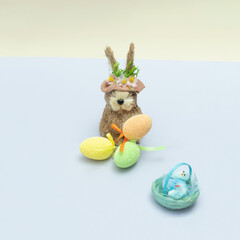 Easter bunny with Easter eggs and chickens in the nest. Multicolored background. Minimalist concept of creative design.