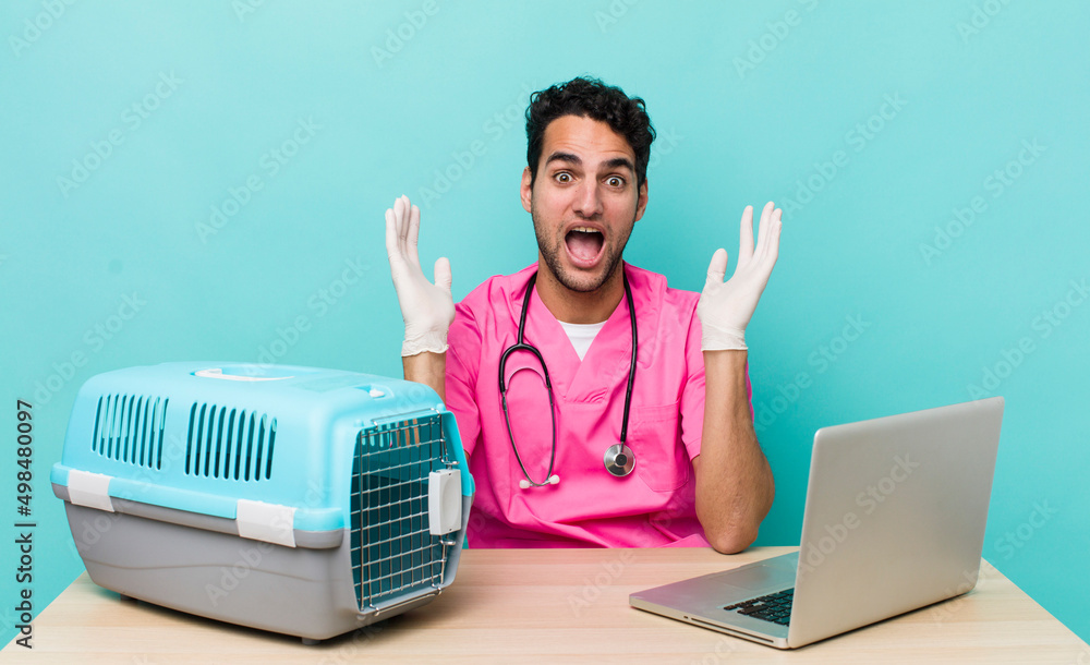 Wall mural hispanic handsome man feeling happy and astonished at something unbelievable. veterinarian concept