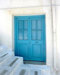Fototapeta na wymiar Blue entrance door by the alley stairs in Chora, capital of Andros island, Greece.