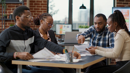 Team of african american businesspeople analyzing charts documents, looking at report statistics...
