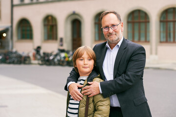 Outdoor portrait of father and son, middle age man with young child posing on the street