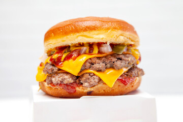 Double decker donut bun burger with beef patties and dressing on a takeaway box.