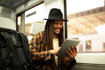 Young man using digital tablet while traveling by a train. Handsome young man traveling by a train.