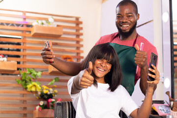 excited african man and woman in a hair salon holding their phones