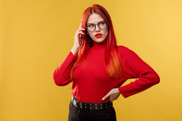 Glamour woman wearing glasses using smartphone on yellow background