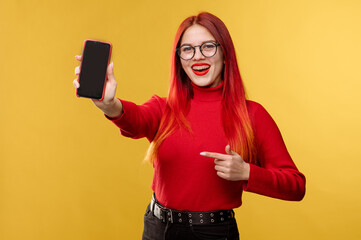 Glamour woman wearing glasses using smartphone on yellow background