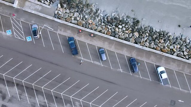Birds eye view of beach parking at Nantasket beach, Massachusetts. Walkers, runner and young man with a dog pass by.