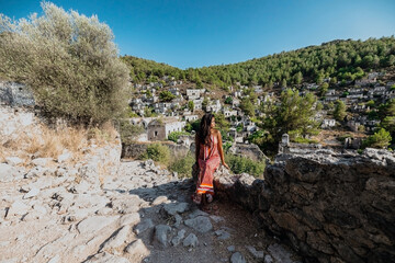 young asian female sitting on a rock staircase in kayakoy ghost town village in fethiye turkey at...