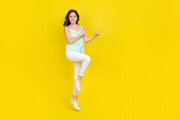 Fototapeta na wymiar Full length photo of good mood charming young female promote recommend product isolated on yellow color background