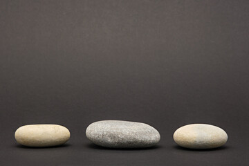 three stone, pebbles on black background, stone podium or platform, showcase