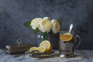 Still life in vintage style, tea with lemon in a faceted glass with a stand, caviar sandwich,...