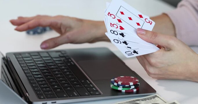Person works with laptop playing cards stack of casino chips