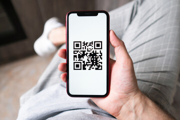 Young man in modern cafe showing smartphone scan QR code for payment 