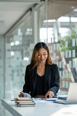 Asian businesswoman sitting working on laptop in office. tax, accounting, financial concept