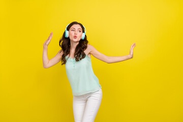 Photo of overjoyed active dancing attractive charming lady listen music in headset isolated on yellow color background