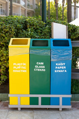 Colorful buckets for sorting garbage glass, plastic and paper standing in the street