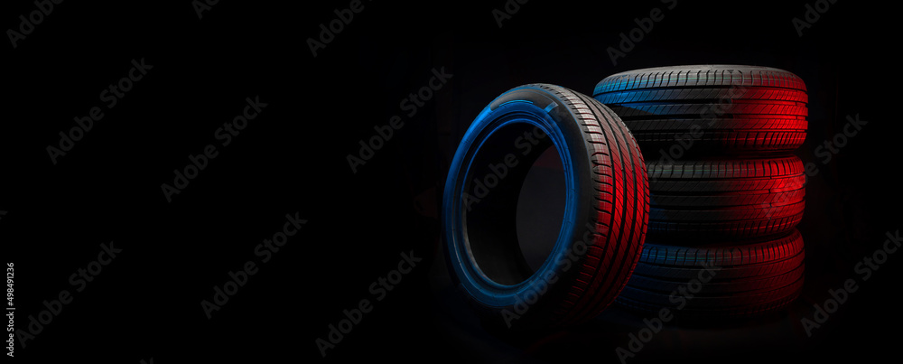 Wall mural New car tires. Group of road wheels on dark background. Summer Tires with asymmetric tread design. Driving car concept.