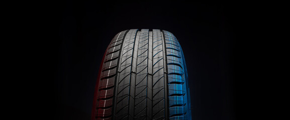 New car tire. Road wheel on dark background. Summer Tire with asymmetric tread design. Driving car concept.